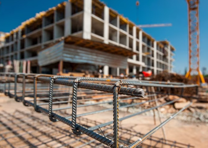 Construction site with steel reinforcement bars in focus and building structure